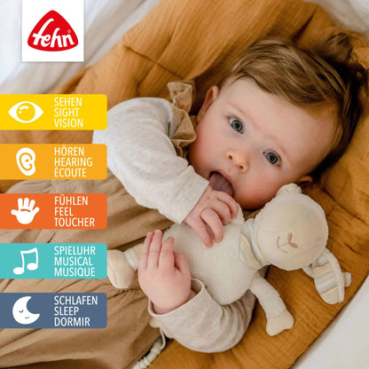 Fehn BabyLOVE owca — poglądowe zdjęcie dziecka z przytulanką na grafice produktu